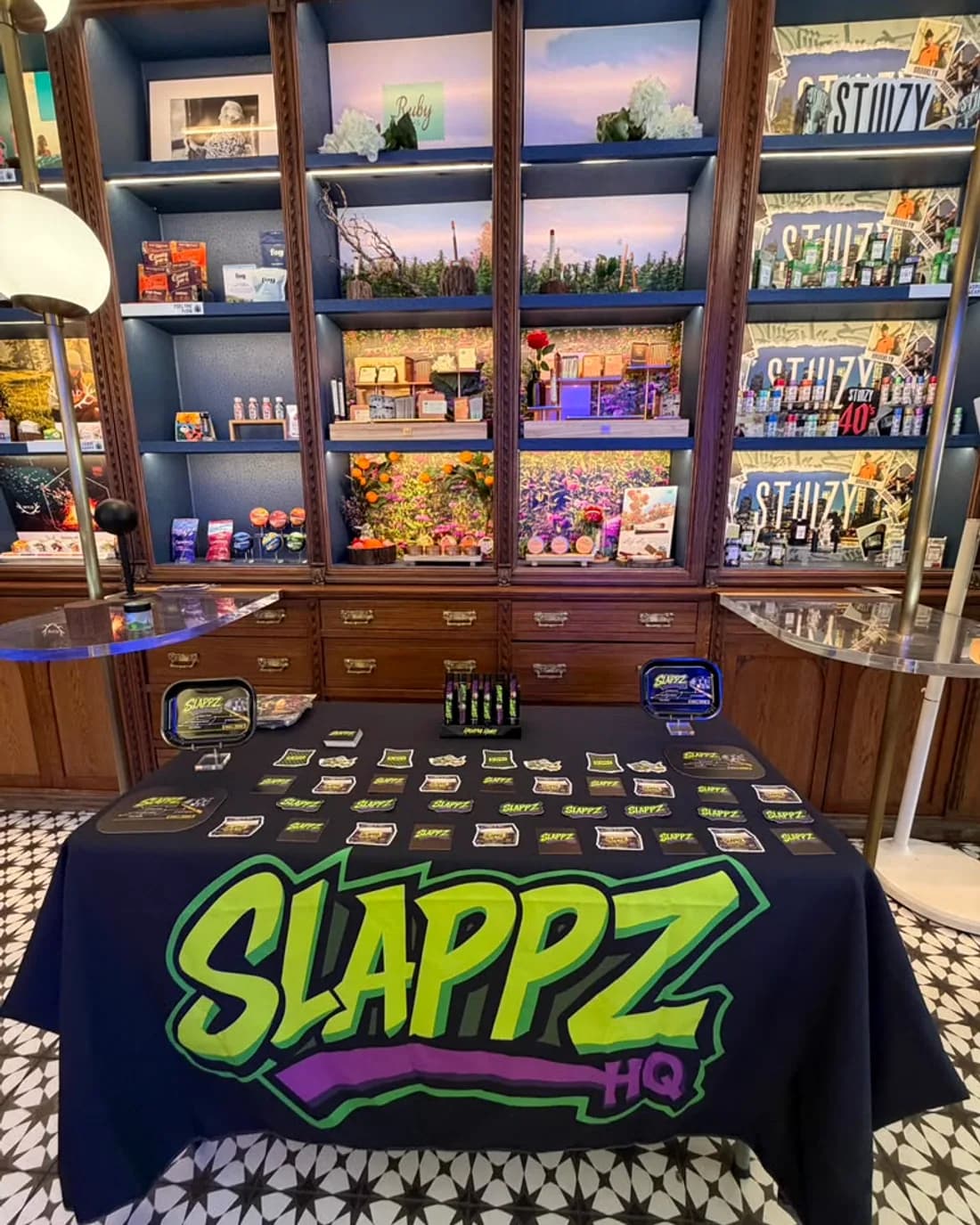 A SLAPPZ HQ branded table laid out with pre-rolls in a wood-panelled dispensary.
